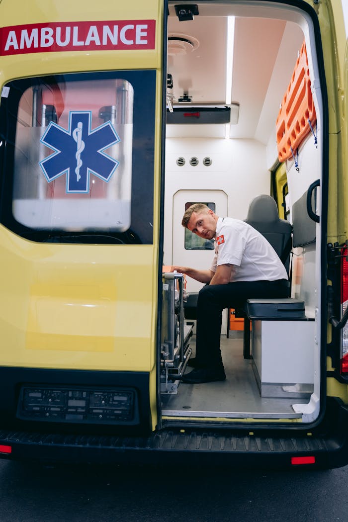 A dedicated paramedic sits inside an open ambulance, ready to assist in emergencies.